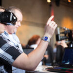 Besucher probieren die Datenbrille und das Navigieren per Handbewegung in der virtuellen Realität